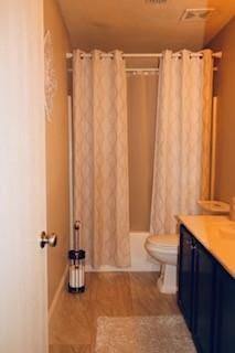 1124 Mazourka Dr, Arlington, TX 76001 - bathroom with vanity, wood finished floors, visible vents, shower / bath combo with shower curtain, and toilet