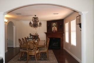 1124 Mazourka Dr, Arlington, TX 76001 - dining room featuring baseboards, decorative columns, arched walkways, a notable chandelier, and a large fireplace