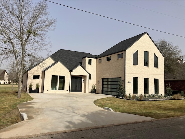 modern farmhouse style home featuring brick siding, a garage, driveway, and a front yard