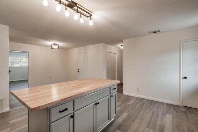 411 N 5th Ave, Munday, TX 76371 - kitchen with wood counters, a kitchen island, visible vents, and light wood finished floors