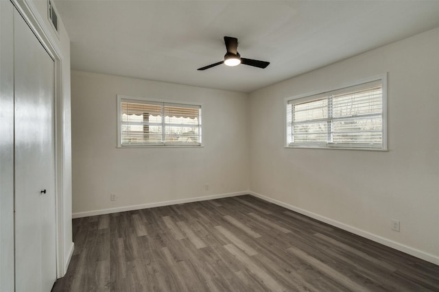 411 N 5th Ave, Munday, TX 76371 - unfurnished bedroom featuring a closet, multiple windows, visible vents, and dark wood-style flooring
