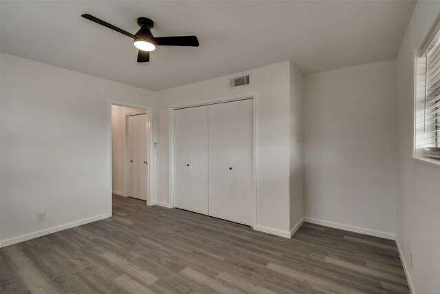 411 N 5th Ave, Munday, TX 76371 - unfurnished bedroom featuring visible vents, ceiling fan, baseboards, wood finished floors, and a closet
