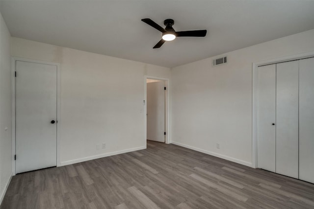 411 N 5th Ave, Munday, TX 76371 - unfurnished bedroom featuring ceiling fan, wood finished floors, visible vents, and baseboards