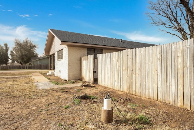 411 N 5th Ave, Munday, TX 76371 - view of side of property featuring brick siding, a shingled roof, and fence