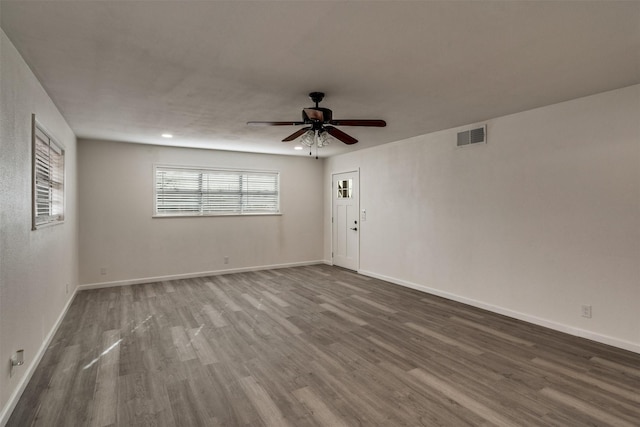 411 N 5th Ave, Munday, TX 76371 - unfurnished room featuring baseboards, wood finished floors, visible vents, and ceiling fan