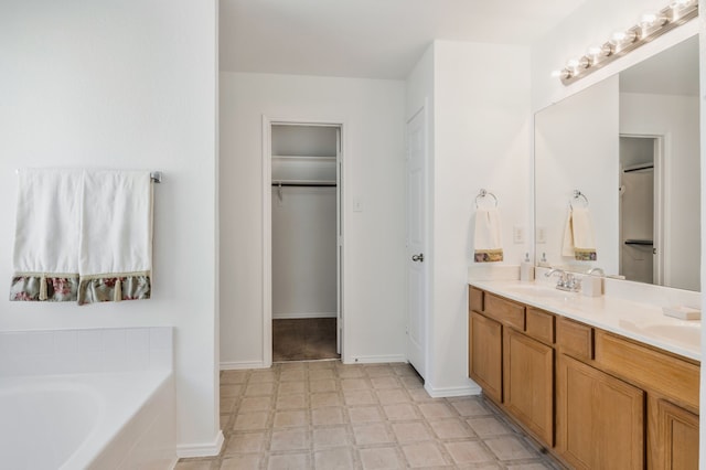 bathroom with tile patterned floors, a walk in closet, a garden tub, a sink, and double vanity