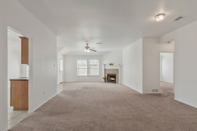 unfurnished living room featuring light carpet, a fireplace, visible vents, and ceiling fan