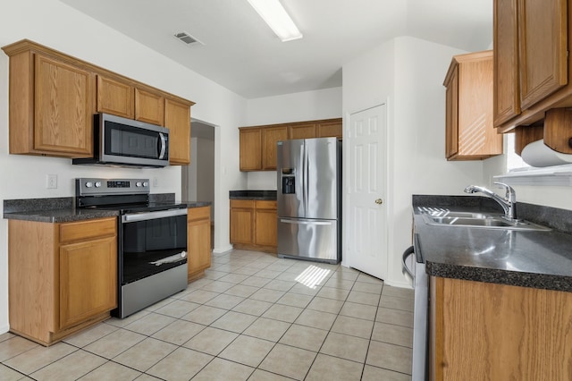 kitchen featuring dark countertops, visible vents, light tile patterned flooring, stainless steel appliances, and a sink