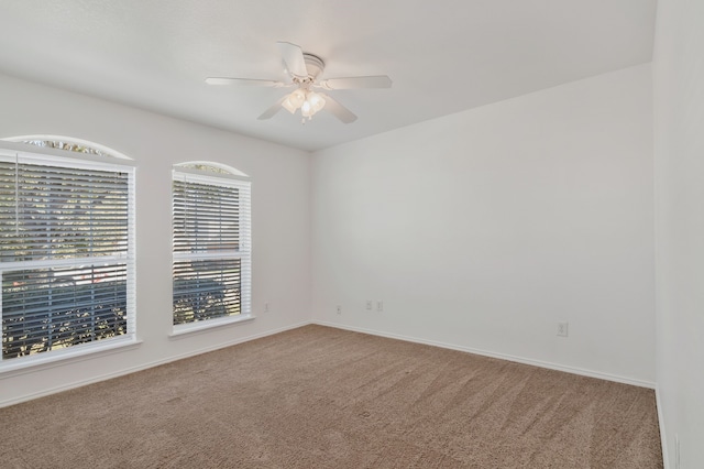 empty room featuring carpet flooring, baseboards, and ceiling fan