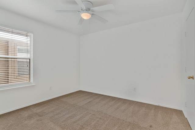 carpeted spare room featuring a ceiling fan and baseboards