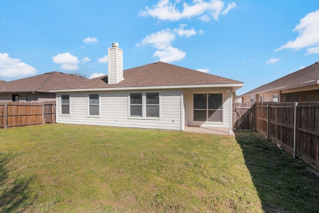 back of house with a fenced backyard, a chimney, a yard, and roof with shingles