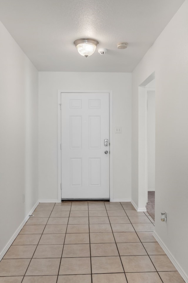 doorway to outside featuring light tile patterned floors, baseboards, and a textured ceiling