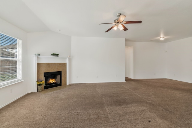 unfurnished living room with carpet, ceiling fan, a tiled fireplace, and vaulted ceiling