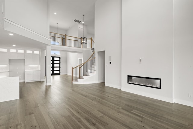 7127 Seagrove Ct, Grand Prairie, TX 75054 - unfurnished living room featuring a towering ceiling, wood finished floors, stairway, recessed lighting, and a glass covered fireplace