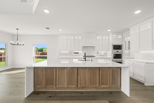 7127 Seagrove Ct, Grand Prairie, TX 75054 - kitchen with premium range hood, oven, black microwave, backsplash, and a chandelier