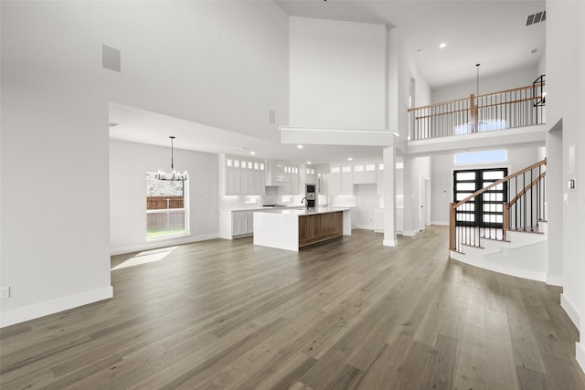 7127 Seagrove Ct, Grand Prairie, TX 75054 - unfurnished living room with a chandelier, plenty of natural light, wood finished floors, a high ceiling, and recessed lighting