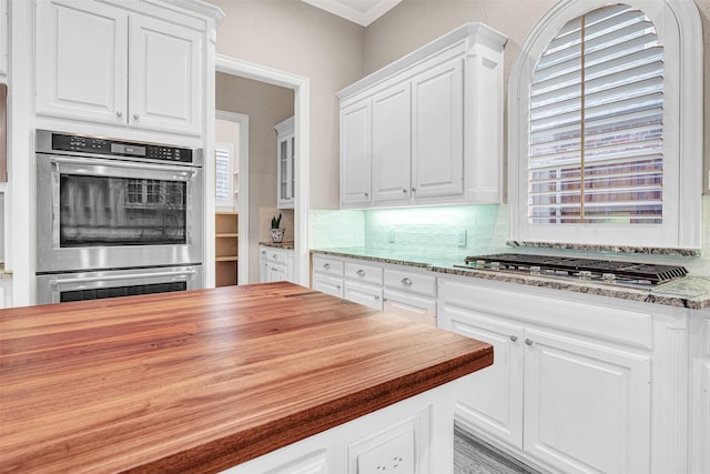 kitchen with white cabinets, backsplash, appliances with stainless steel finishes, and wood counters