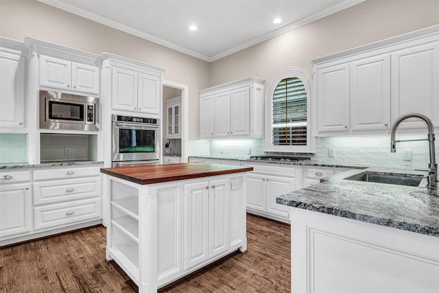 kitchen featuring a sink, crown molding, butcher block counters, stainless steel appliances, and open shelves