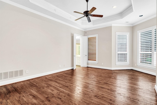 unfurnished room with visible vents, crown molding, wood finished floors, a raised ceiling, and a ceiling fan