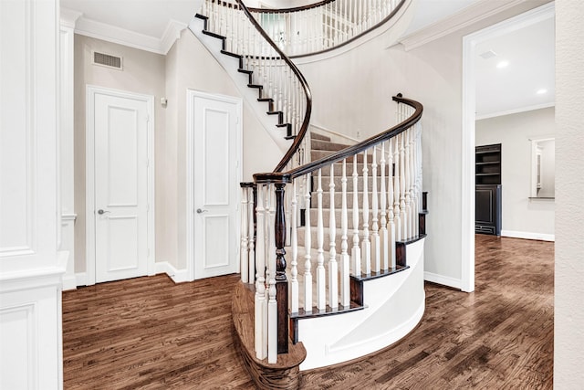 stairway with crown molding, wood finished floors, baseboards, and visible vents