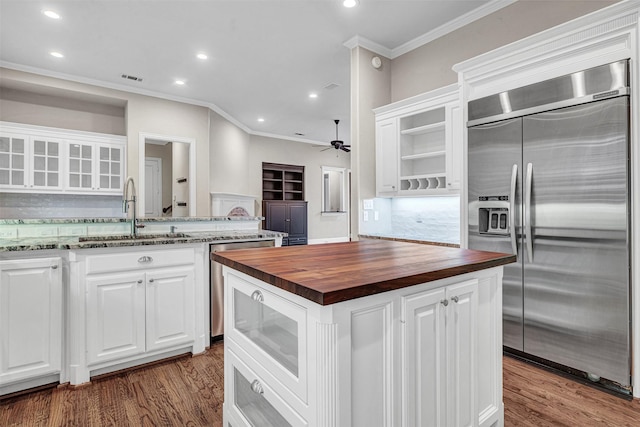 kitchen featuring a ceiling fan, a sink, white cabinetry, stainless steel appliances, and wooden counters