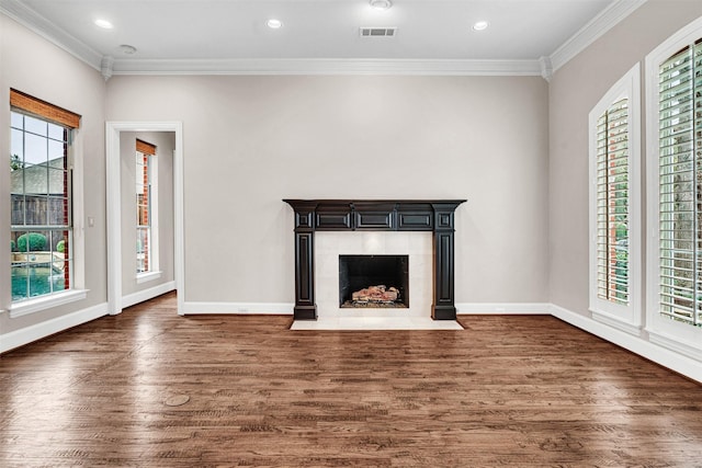 unfurnished living room featuring visible vents, ornamental molding, a tiled fireplace, wood finished floors, and baseboards