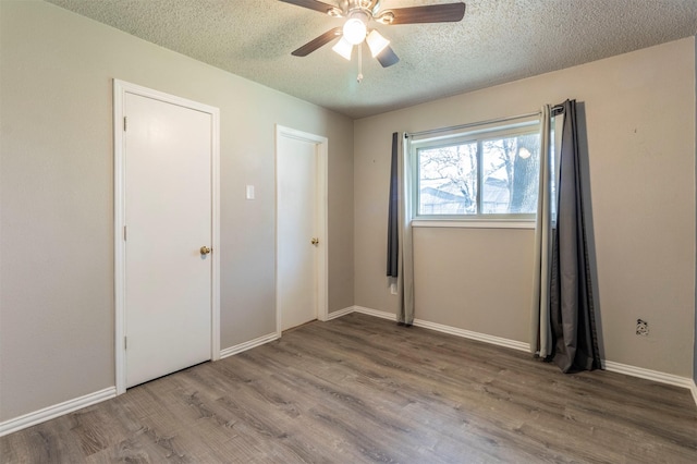 unfurnished bedroom featuring ceiling fan, wood finished floors, baseboards, and a textured ceiling