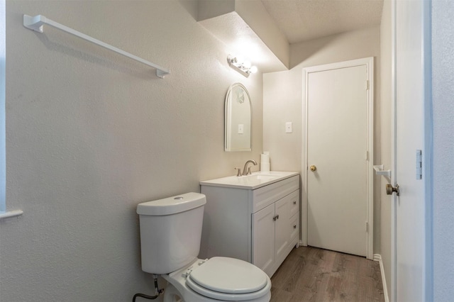 bathroom featuring toilet, vanity, and wood finished floors