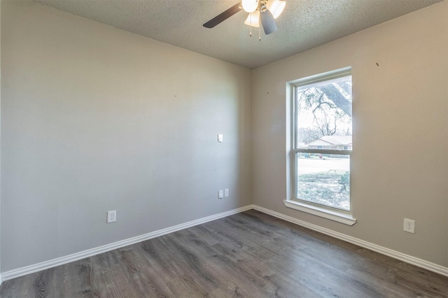 unfurnished room featuring a wealth of natural light, baseboards, dark wood-type flooring, and a ceiling fan