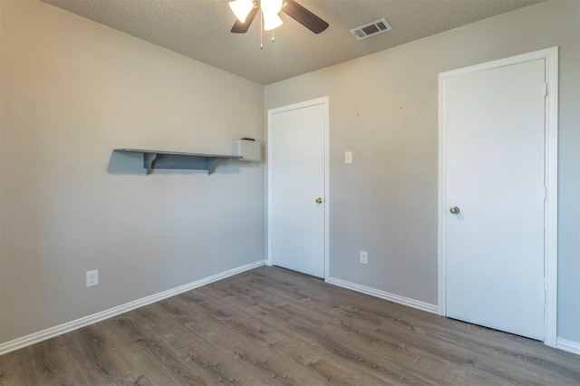 unfurnished room featuring visible vents, baseboards, wood finished floors, and a ceiling fan