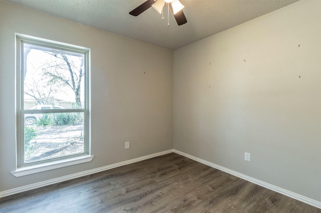 spare room featuring a textured ceiling, dark wood-type flooring, baseboards, and a ceiling fan