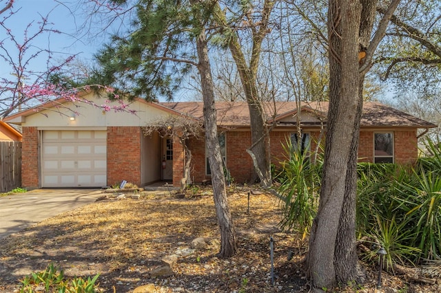 ranch-style home featuring a garage, brick siding, driveway, and fence