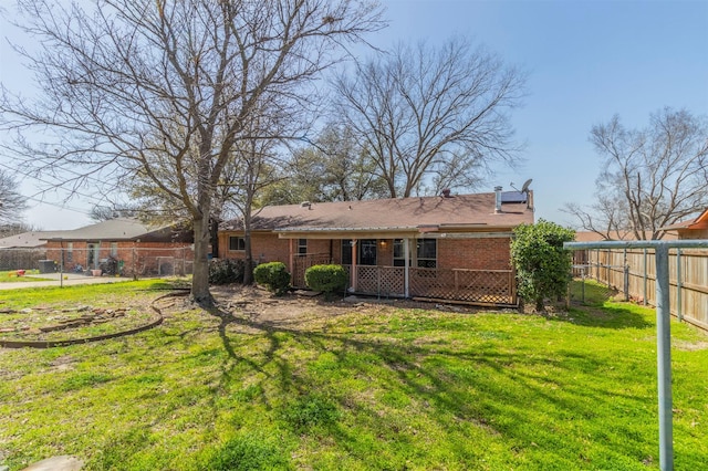 back of house featuring brick siding, a lawn, and a fenced backyard