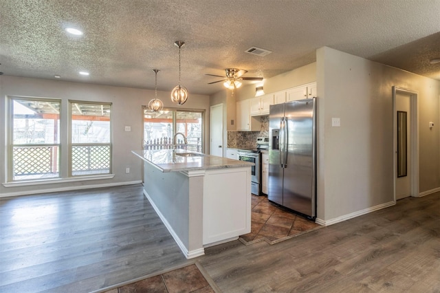 kitchen featuring visible vents, a sink, stainless steel appliances, white cabinets, and decorative backsplash