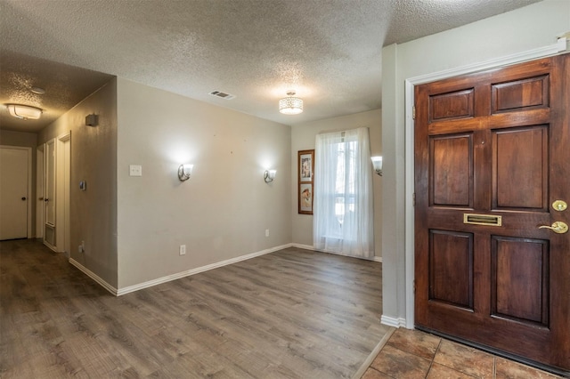 foyer with visible vents, a textured ceiling, baseboards, and wood finished floors