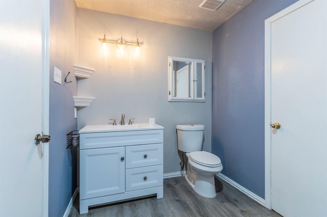 bathroom with vanity, wood finished floors, visible vents, baseboards, and toilet