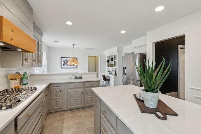 kitchen featuring light countertops, custom exhaust hood, gray cabinets, and stainless steel appliances