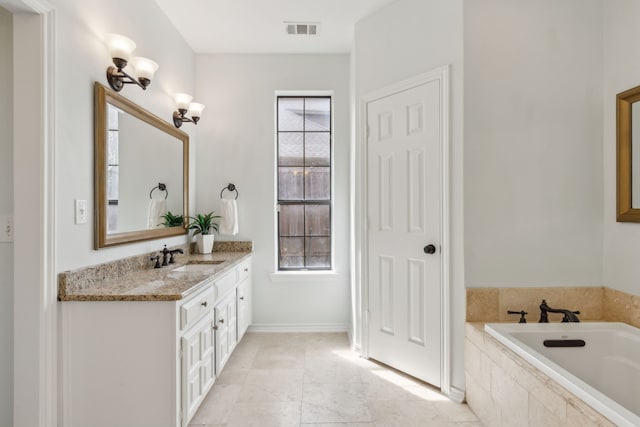 bathroom with vanity, a garden tub, and visible vents