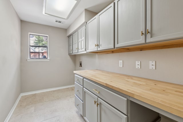 clothes washing area featuring washer hookup, cabinet space, visible vents, and baseboards