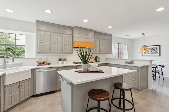 kitchen with a sink, gray cabinets, light countertops, and stainless steel dishwasher