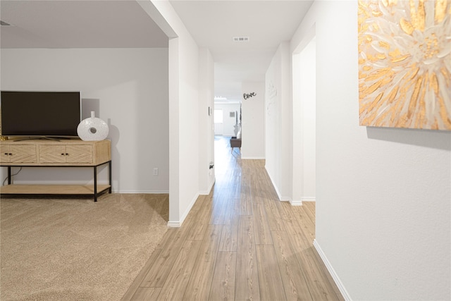 hallway with visible vents, baseboards, and wood finished floors