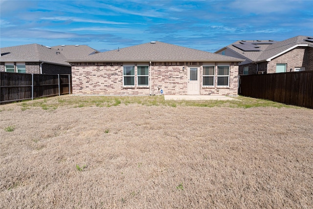 back of house with brick siding, a patio area, a shingled roof, and a fenced backyard