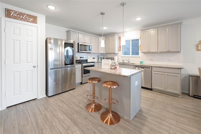 kitchen with stainless steel appliances, a kitchen bar, light wood-style flooring, and a center island