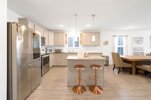 kitchen featuring a kitchen island, light wood-style flooring, a sink, stainless steel appliances, and backsplash
