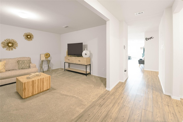 living room with baseboards, visible vents, and light wood finished floors