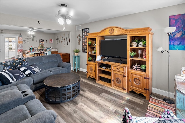 living area featuring visible vents, baseboards, a ceiling fan, and wood finished floors