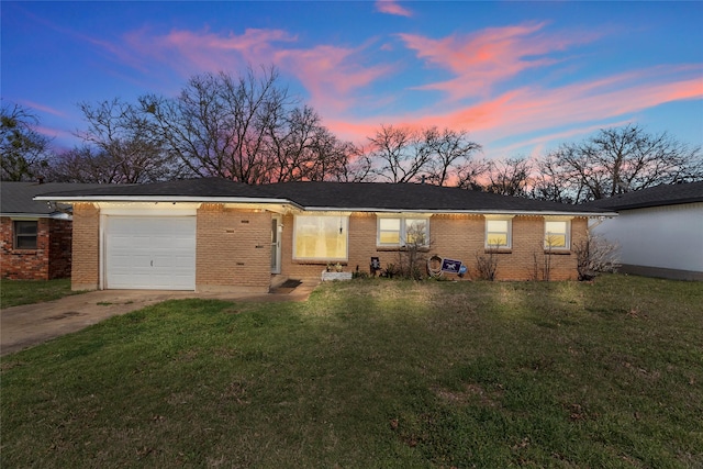 ranch-style house with brick siding, an attached garage, a lawn, and concrete driveway