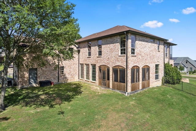 back of house featuring brick siding, a yard, and fence