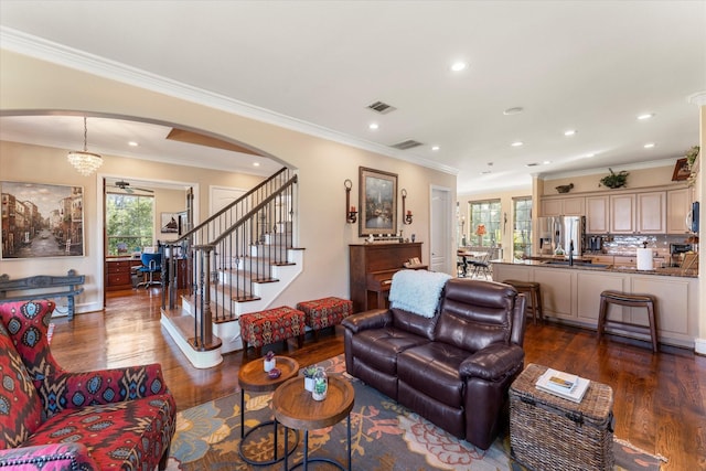 living room featuring wood finished floors, visible vents, recessed lighting, arched walkways, and ornamental molding