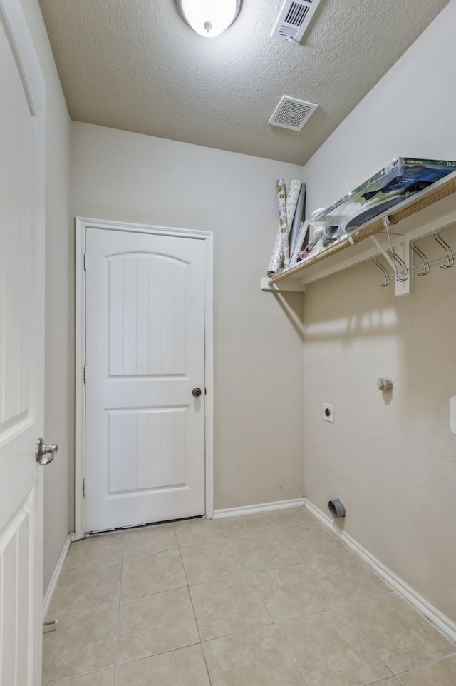 clothes washing area with hookup for an electric dryer, visible vents, a textured ceiling, and laundry area
